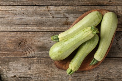 Photo of Raw green zucchinis on wooden table, top view. Space for text