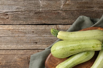 Photo of Raw green zucchinis on wooden table, top view. Space for text