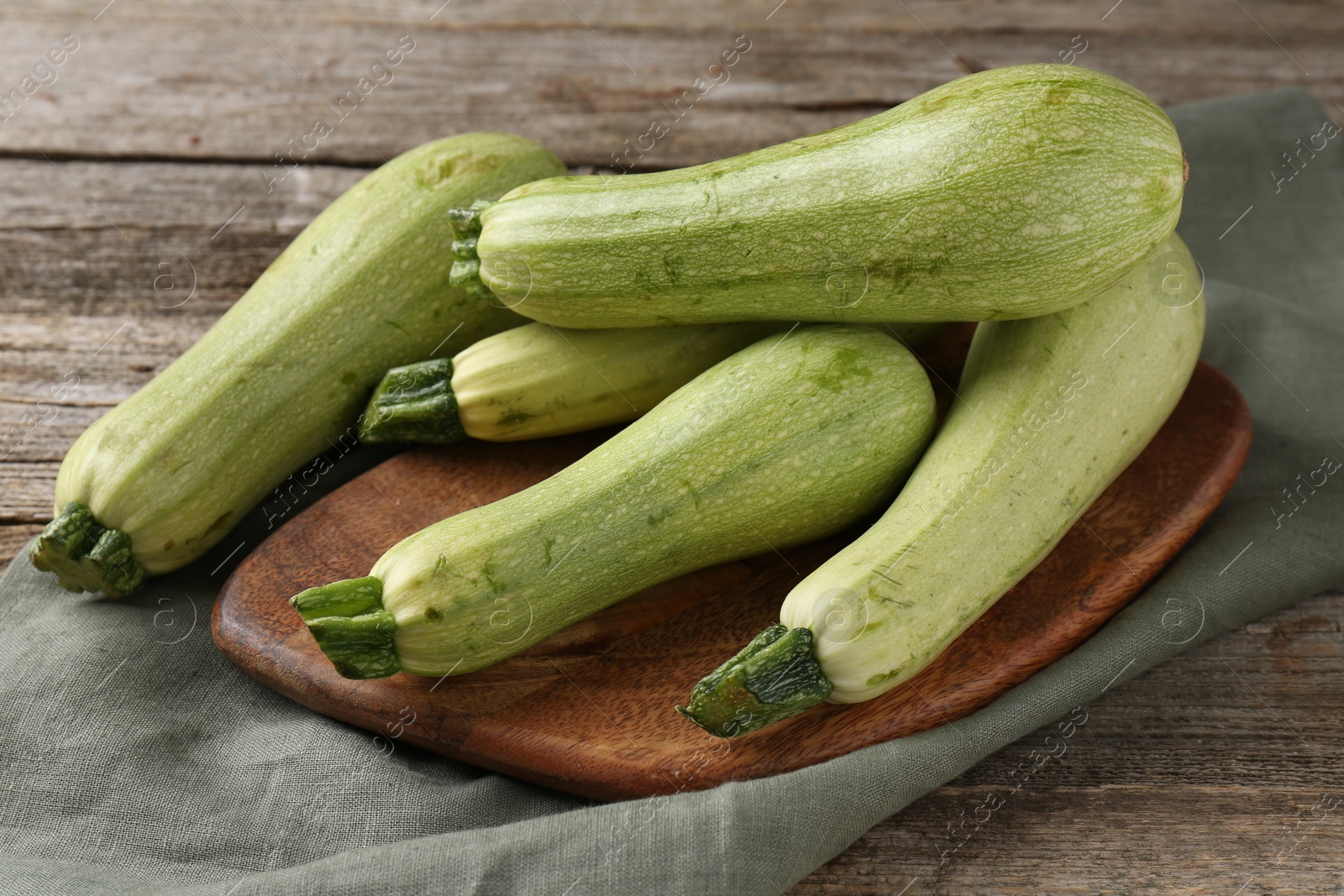 Photo of Raw ripe green zucchinis on wooden table