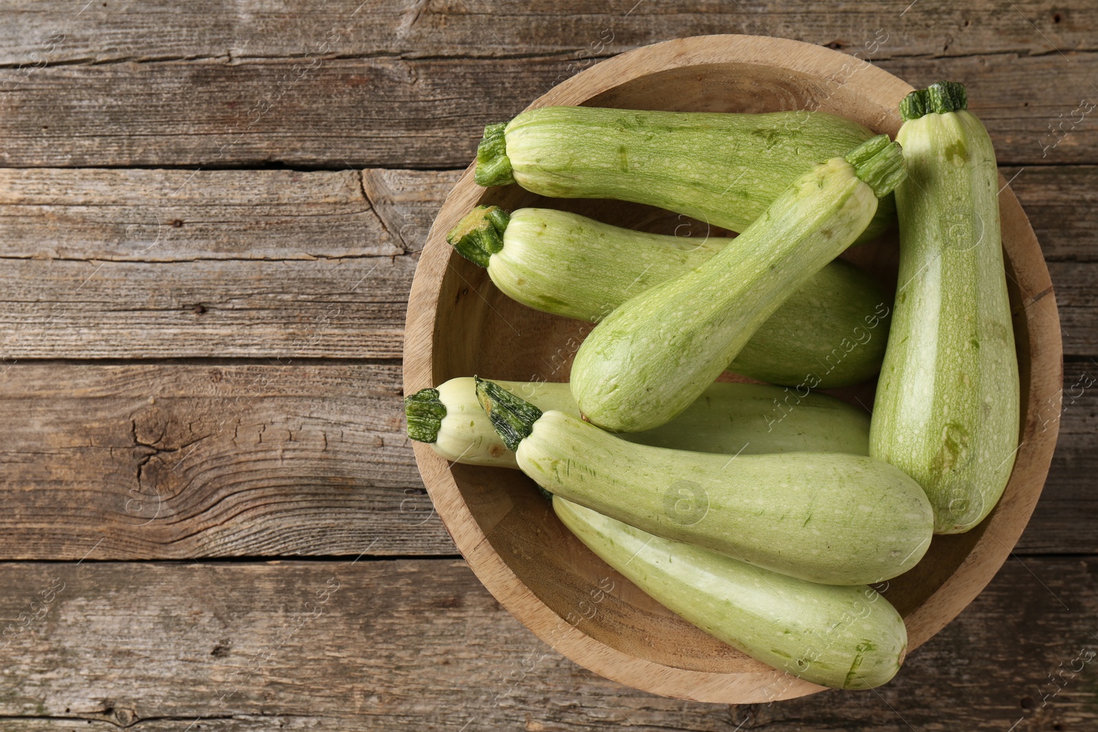 Photo of Raw green zucchinis on wooden table, top view. Space for text