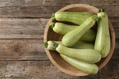 Photo of Raw green zucchinis on wooden table, top view. Space for text