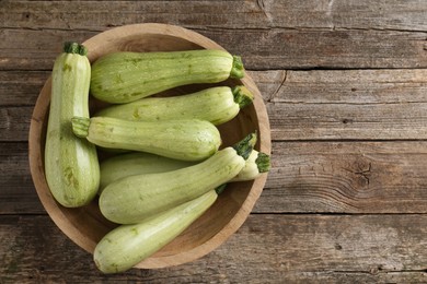 Photo of Raw green zucchinis on wooden table, top view. Space for text