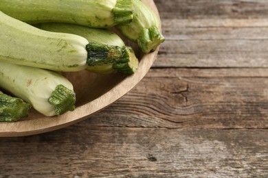 Photo of Raw green zucchinis on wooden table, space for text