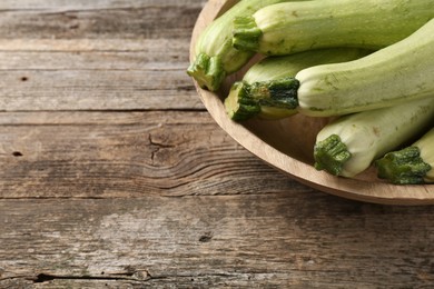 Photo of Raw green zucchinis on wooden table, space for text