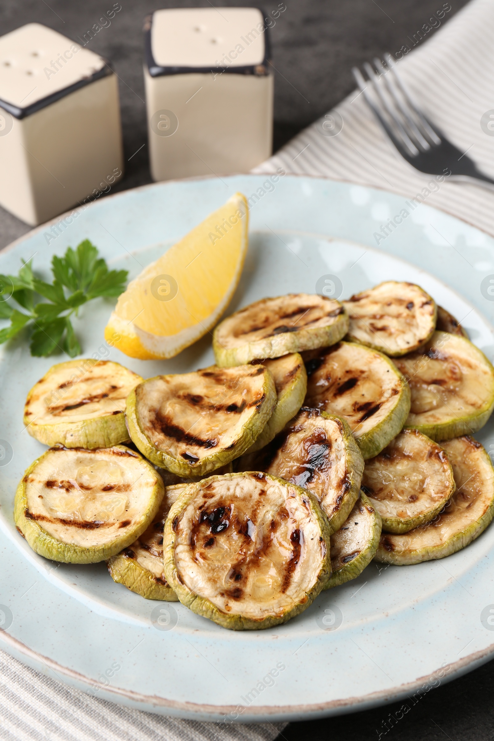 Photo of Tasty grilled zucchini slices served on grey table