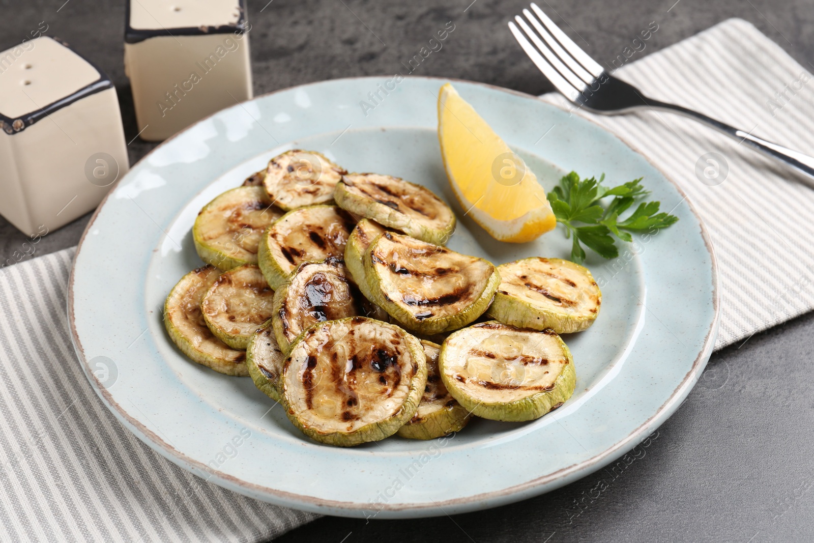 Photo of Tasty grilled zucchini slices served on grey table