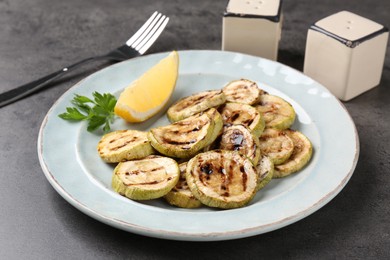 Photo of Tasty grilled zucchini slices served on grey table