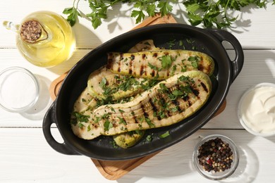 Photo of Tasty grilled zucchini slices served on white wooden table, flat lay