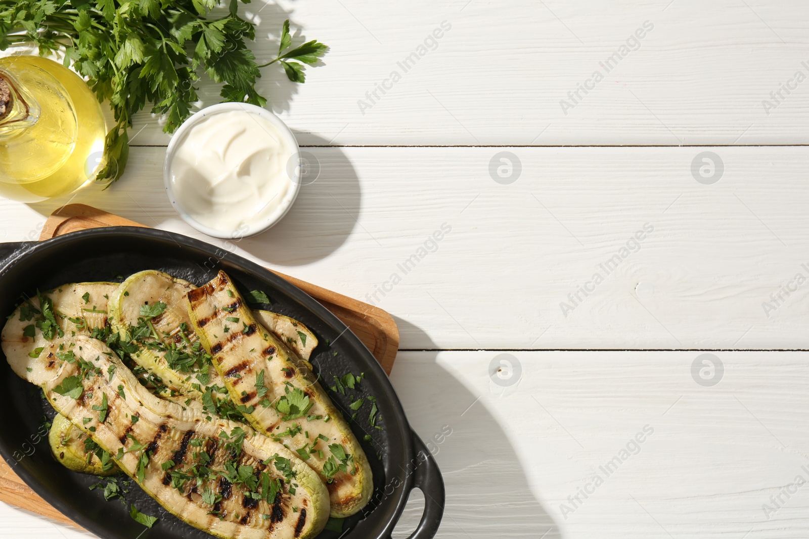 Photo of Tasty grilled zucchini slices served on white wooden table, flat lay. Space for text