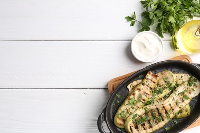 Photo of Tasty grilled zucchini slices served on white wooden table, flat lay. Space for text