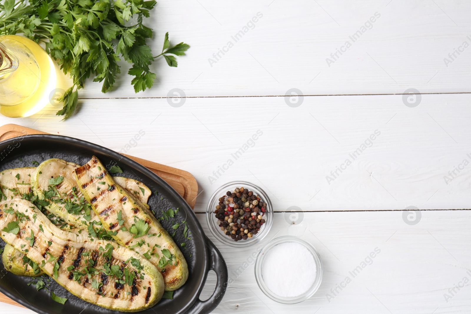 Photo of Tasty grilled zucchini slices served on white wooden table, flat lay. Space for text