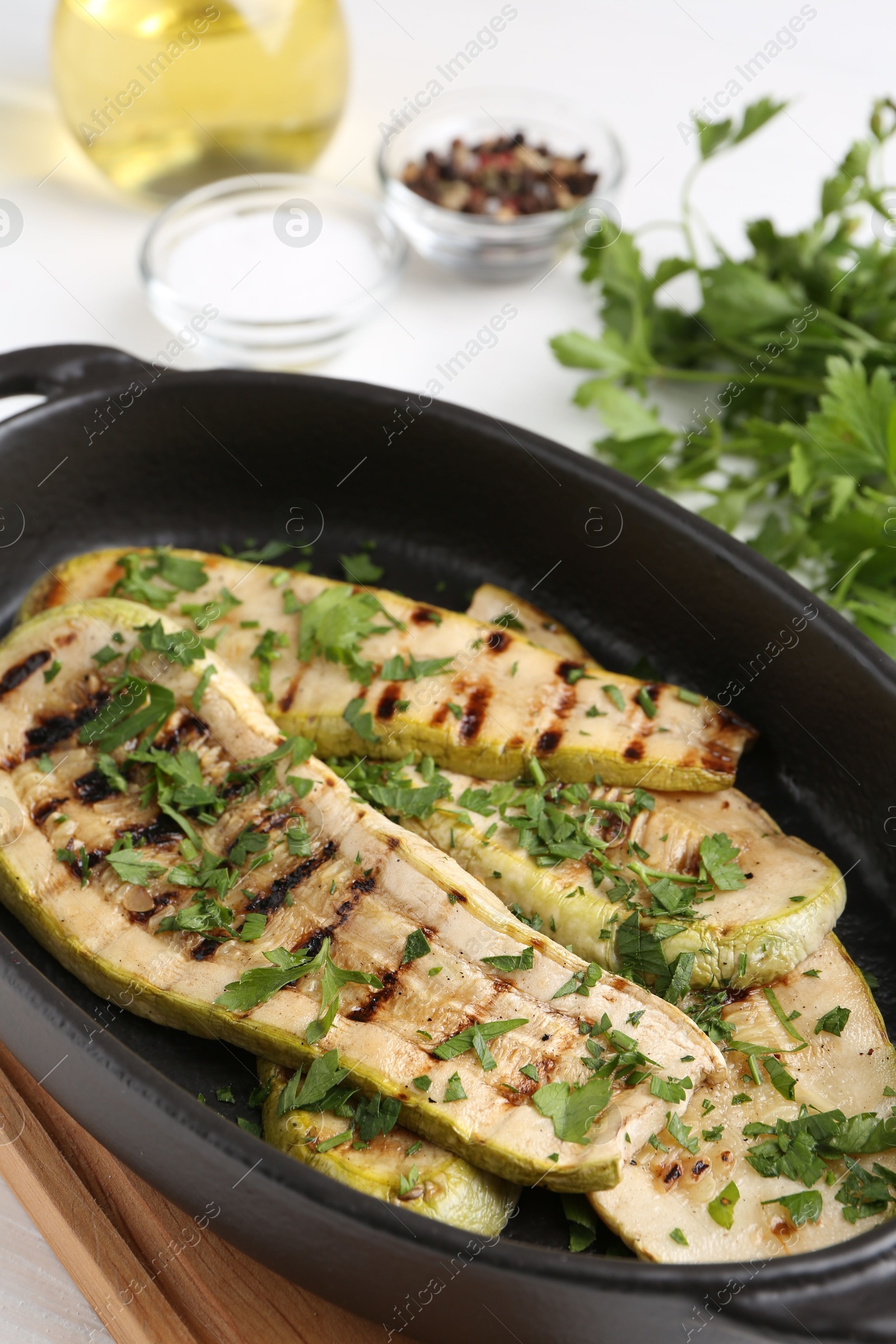 Photo of Tasty grilled zucchini slices in dish on white table