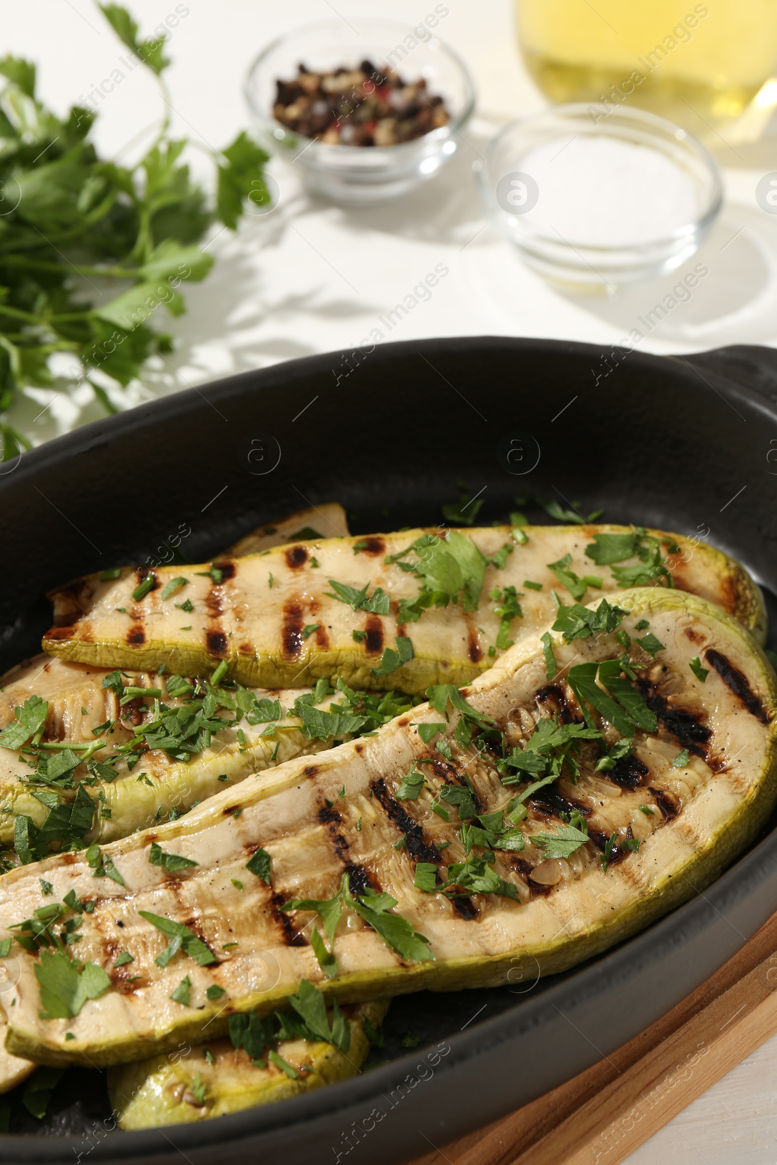 Photo of Tasty grilled zucchini slices in dish on white table