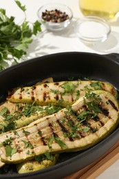 Tasty grilled zucchini slices in dish on white table