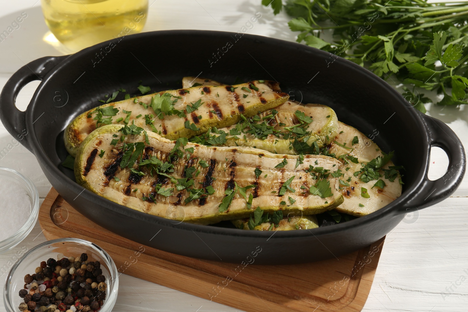 Photo of Tasty grilled zucchini slices in dish on white wooden table