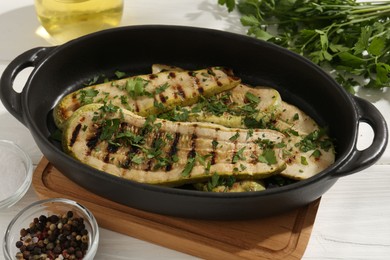 Photo of Tasty grilled zucchini slices in dish on white wooden table