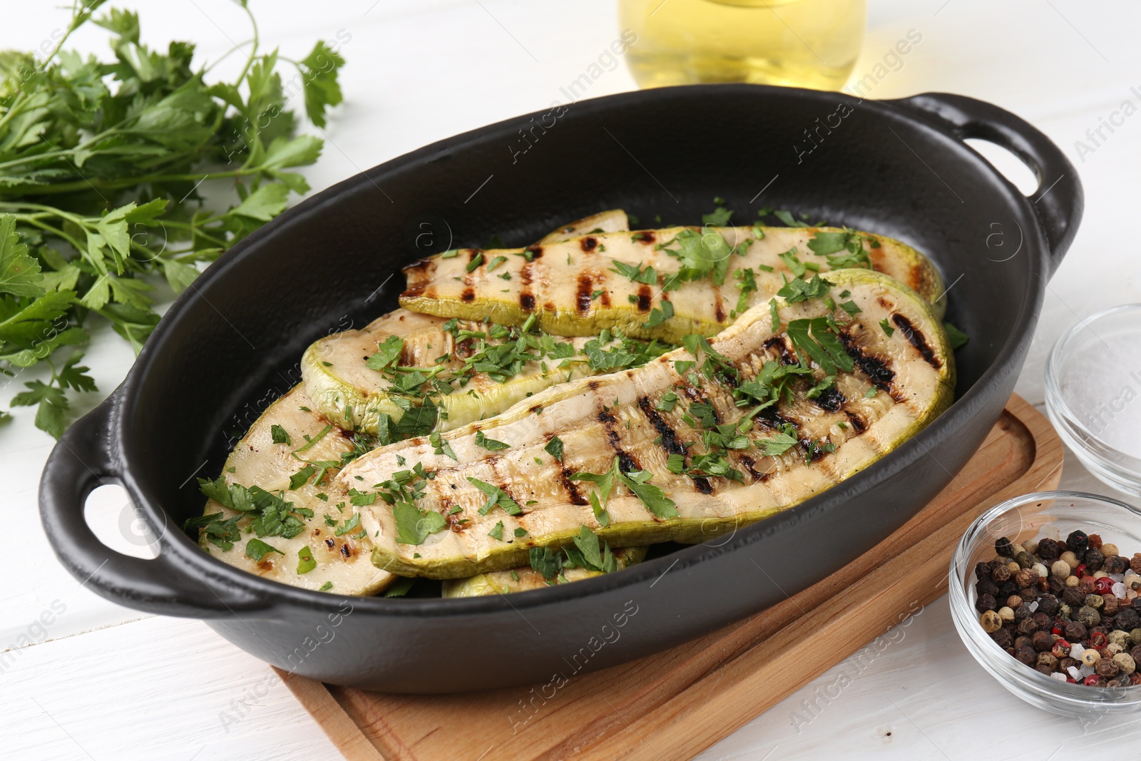 Photo of Tasty grilled zucchini slices in dish on white wooden table