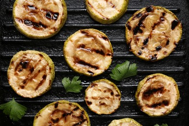 Tasty grilled zucchini slices with parsley on frying pan, flat lay