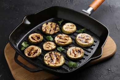 Tasty grilled zucchini slices with parsley in frying pan on grey textured table