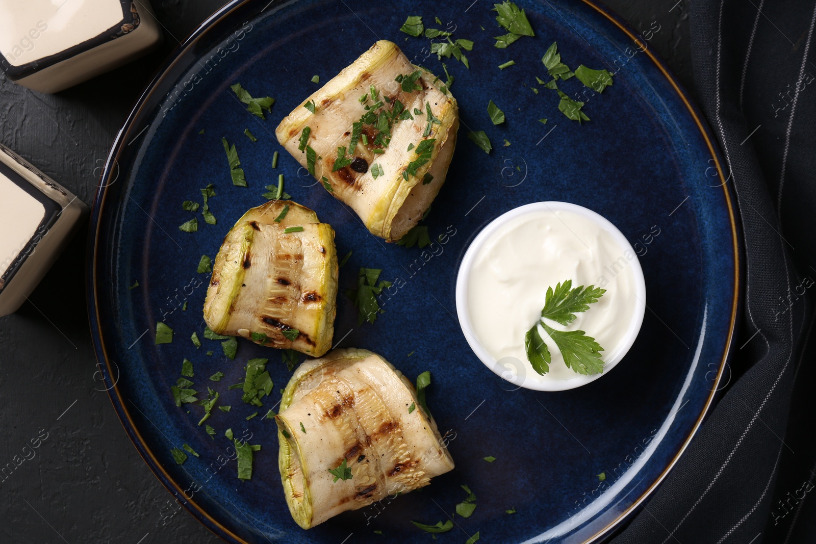 Photo of Tasty grilled zucchini slices served with sauce on grey table, flat lay