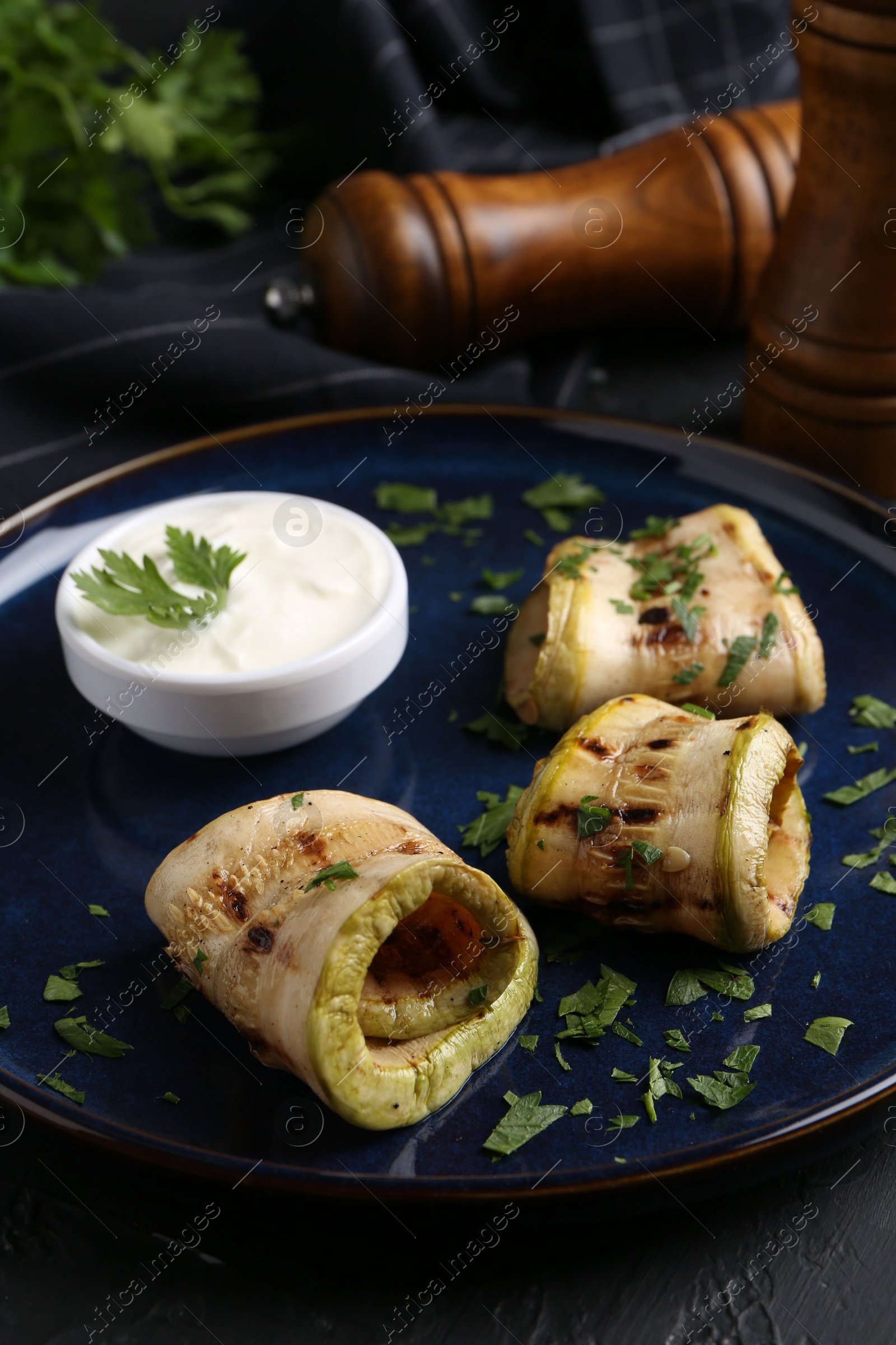 Photo of Tasty grilled zucchini slices served with sauce on table