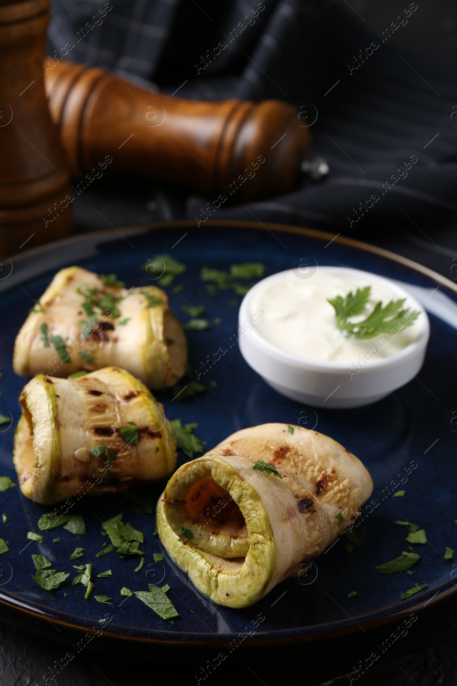 Photo of Tasty grilled zucchini slices served with sauce on table