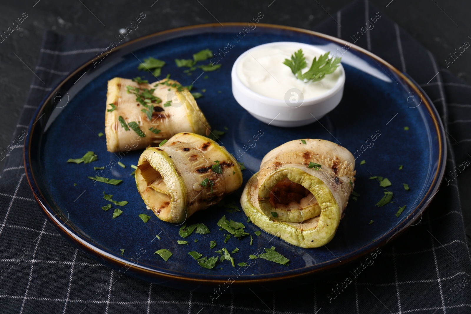 Photo of Tasty grilled zucchini slices served with sauce on table