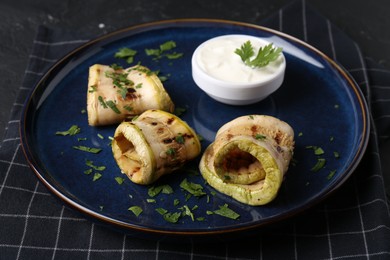 Photo of Tasty grilled zucchini slices served with sauce on table