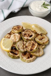 Tasty grilled courgette slices with lemon on grey table