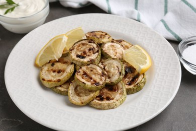 Photo of Tasty grilled courgette slices with lemon on grey table