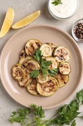 Tasty grilled courgette slices served on grey textured table, flat lay