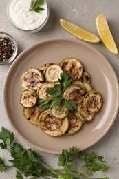 Photo of Tasty grilled courgette slices served on grey textured table, flat lay