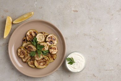 Photo of Tasty grilled courgette slices served on grey textured table, flat lay. Space for text