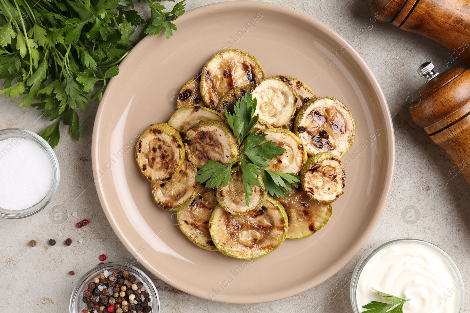 Photo of Tasty grilled courgette slices served on grey textured table, flat lay