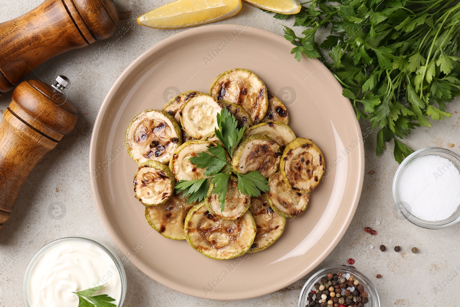 Photo of Tasty grilled courgette slices served on grey textured table, flat lay