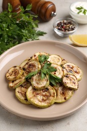 Tasty grilled courgette slices with parsley on grey table