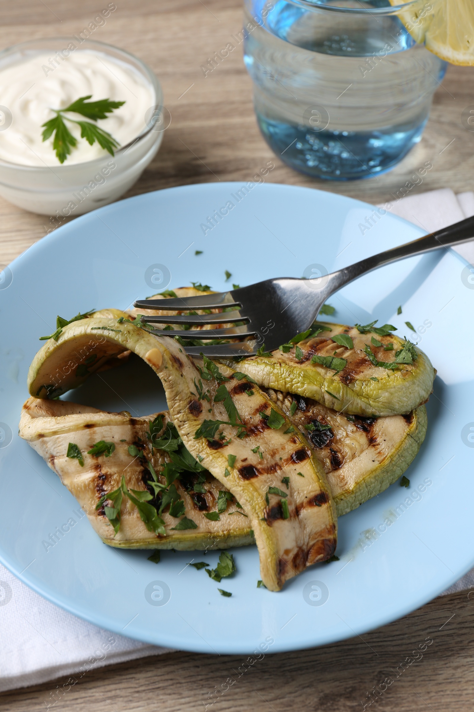 Photo of Tasty grilled courgette slices served on wooden table