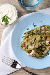 Tasty grilled courgette slices served on wooden table, flat lay