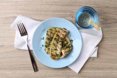 Photo of Tasty grilled courgette slices served on wooden table, flat lay