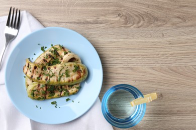 Photo of Tasty grilled courgette slices served on wooden table, flat lay. Space for text