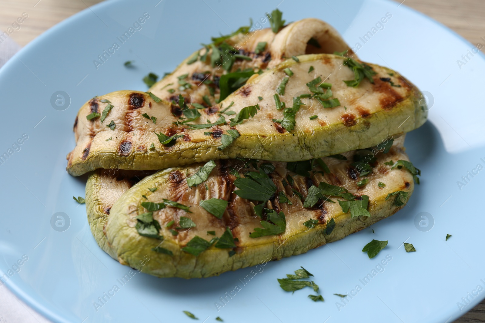 Photo of Tasty grilled courgette slices with parsley on table, closeup