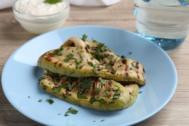 Tasty grilled courgette slices with parsley on wooden table