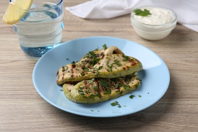 Photo of Tasty grilled courgette slices served on wooden table