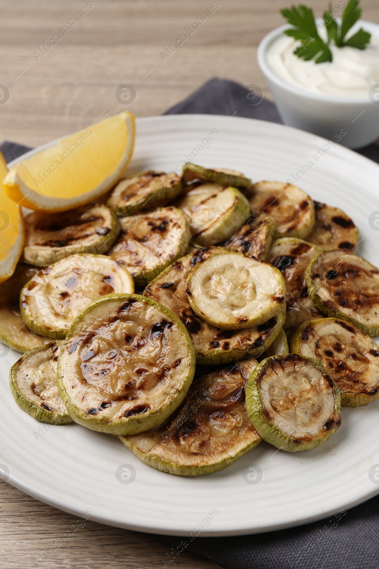 Photo of Tasty grilled courgette slices with lemon on wooden table