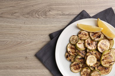 Photo of Tasty grilled courgette slices with lemon on wooden table, top view. Space for text