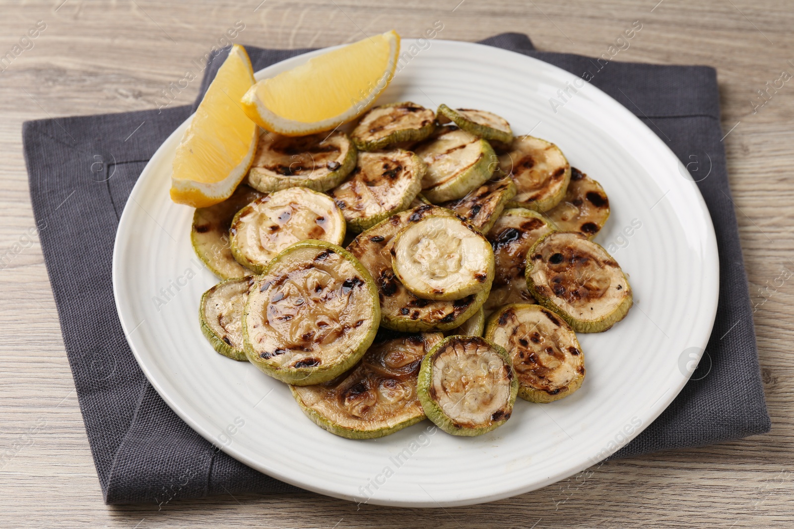 Photo of Tasty grilled courgette slices with lemon on wooden table