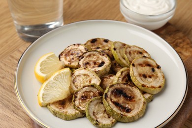 Tasty grilled courgette slices with lemon on wooden table