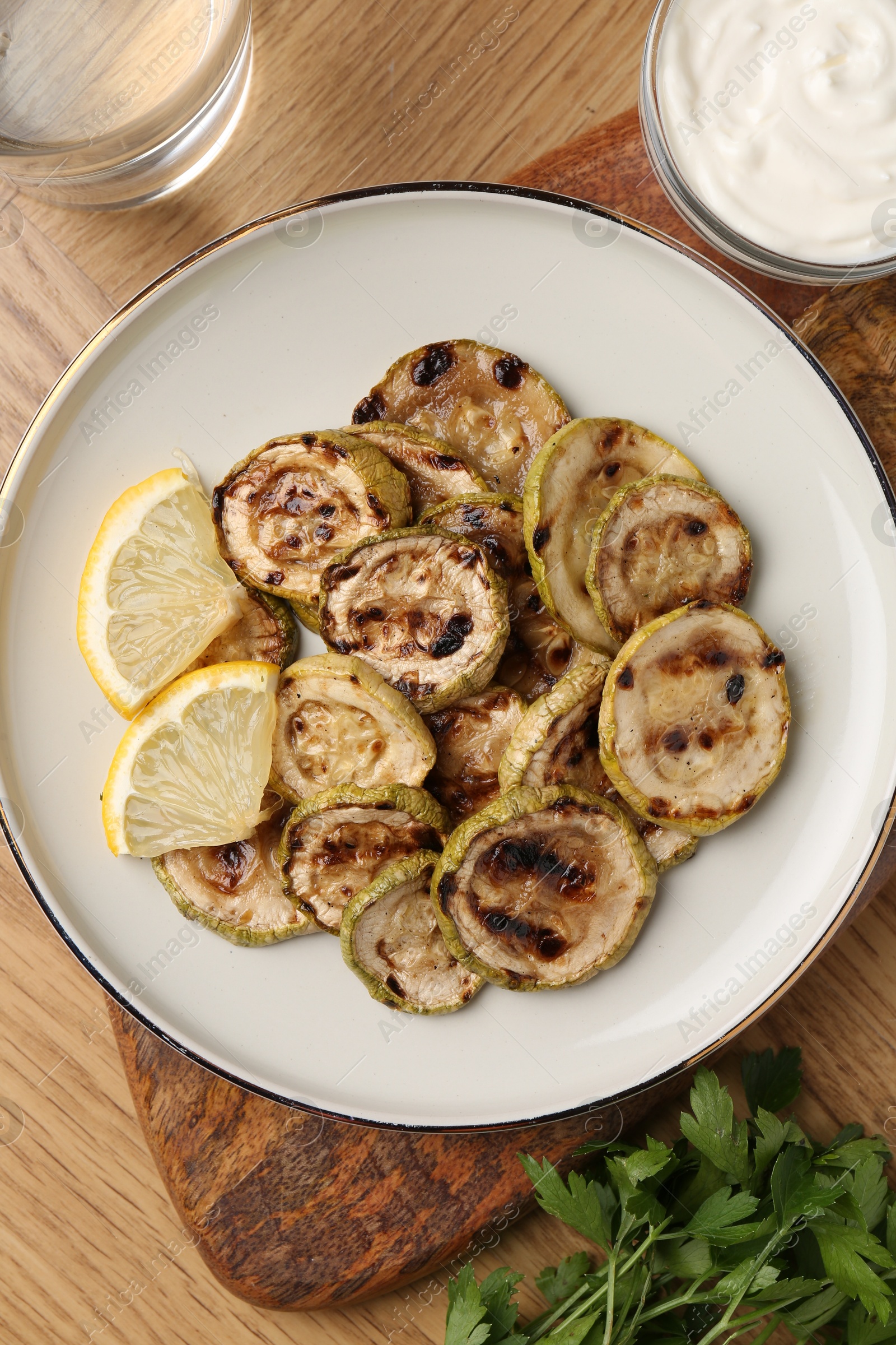 Photo of Tasty grilled courgette slices served on wooden table, flat lay