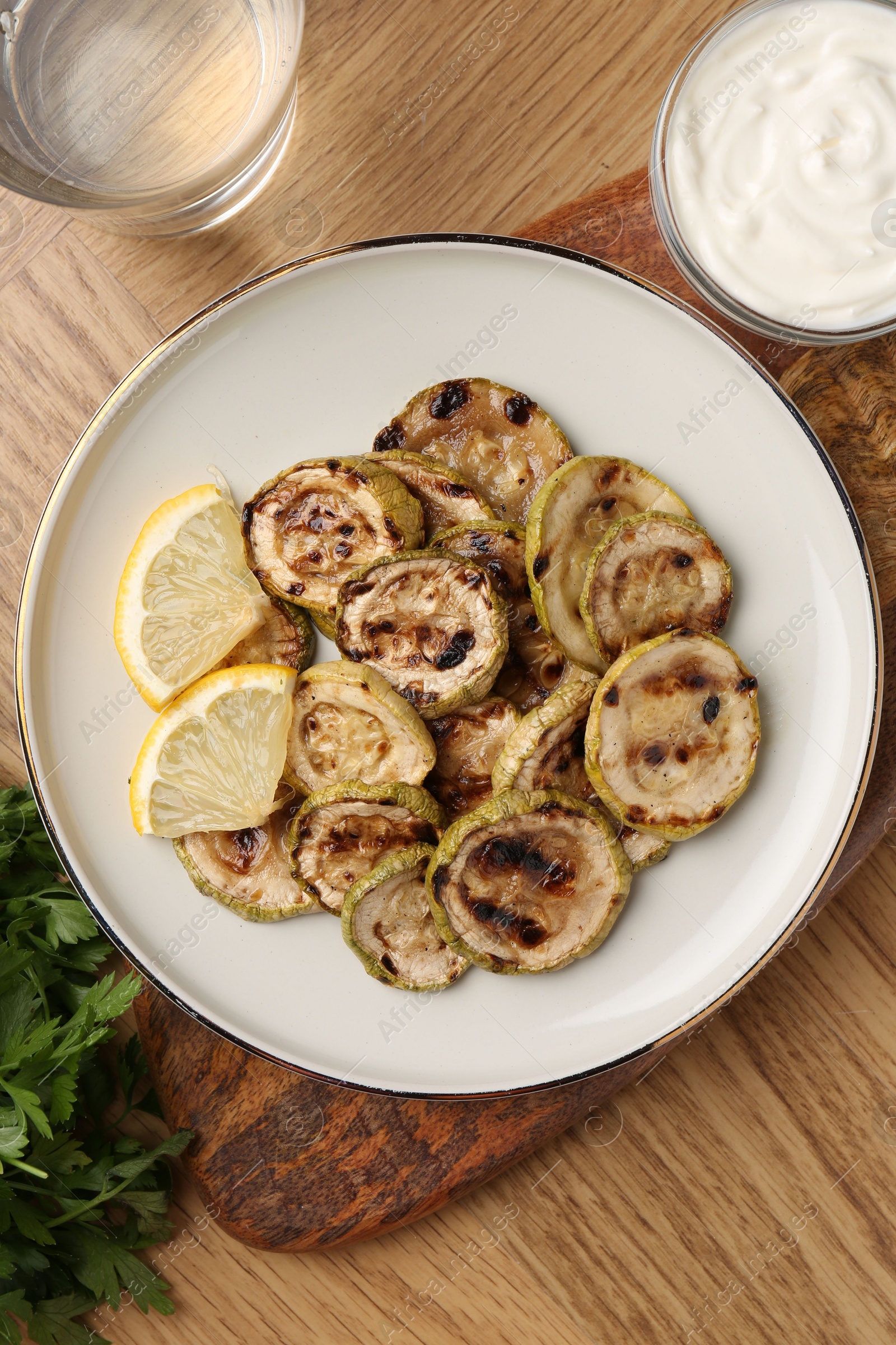 Photo of Tasty grilled courgette slices served on wooden table, flat lay