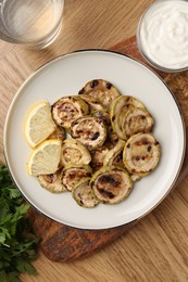 Photo of Tasty grilled courgette slices served on wooden table, flat lay